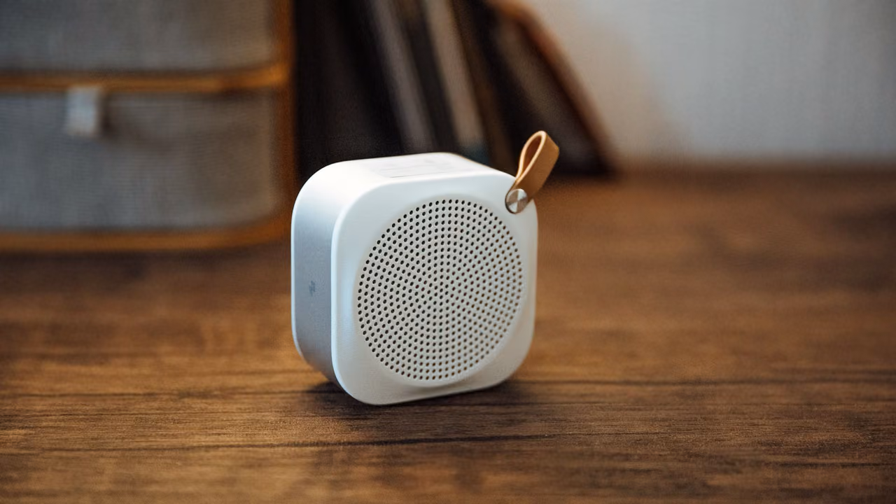Small white portable speaker on a wooden table