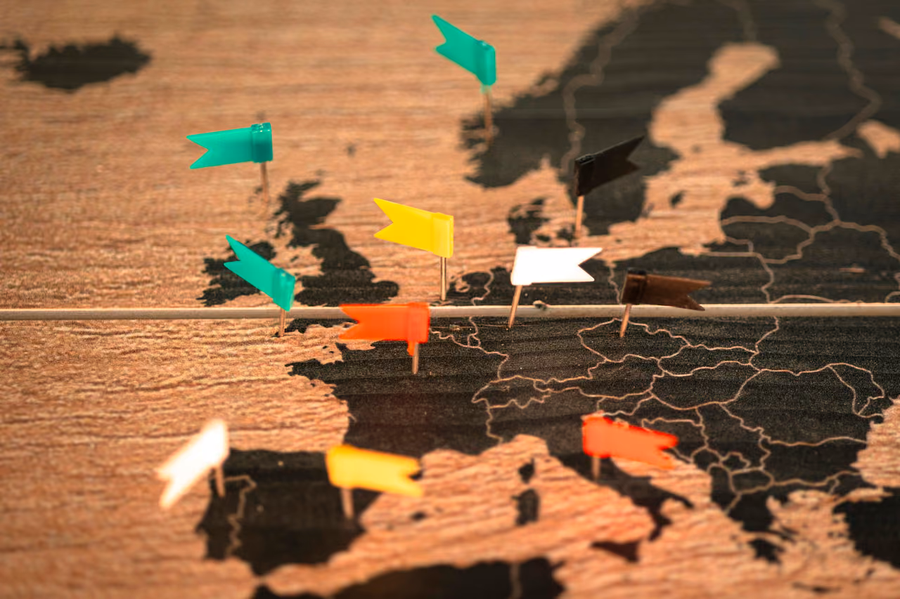 Colored pin flags on a wooden map of Europe