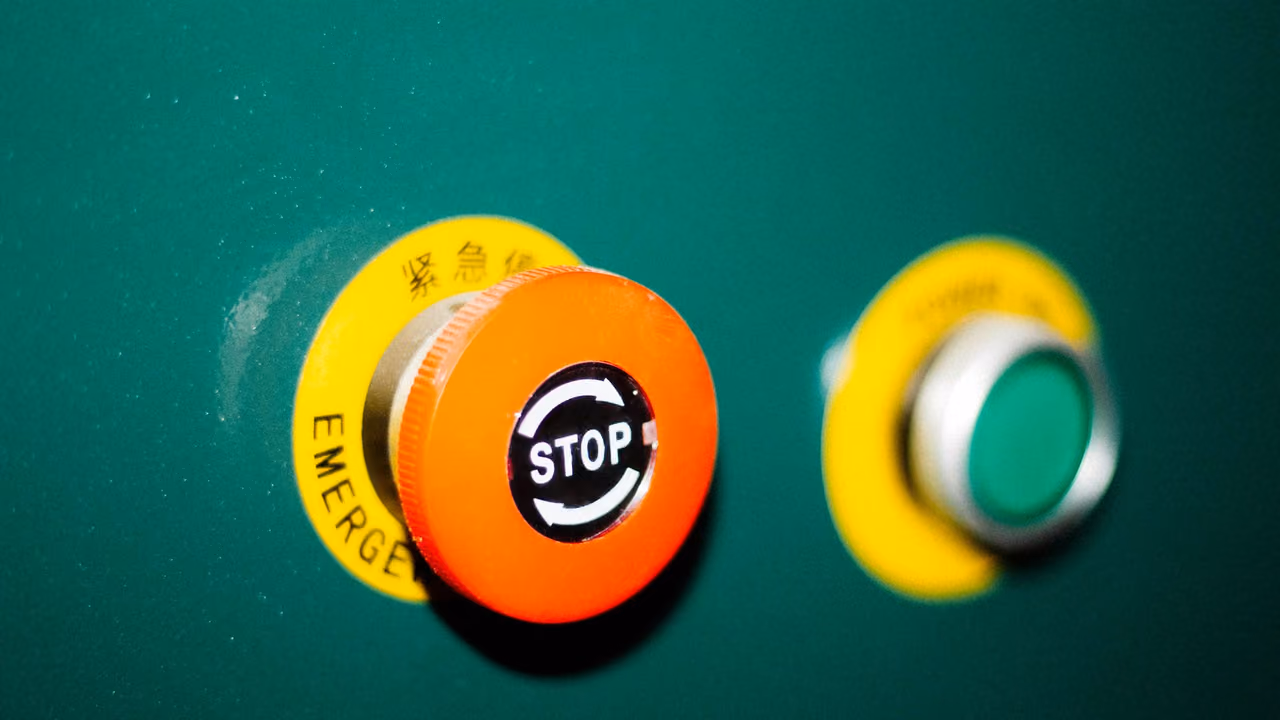 Emergency stop button and a green start button on a machine control cabinet