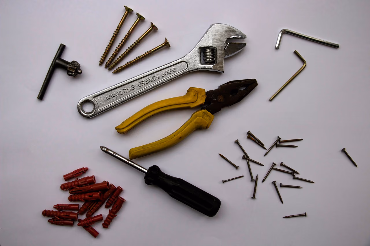 Hand tools, screws and wall plugs laid out neatly on a light surface