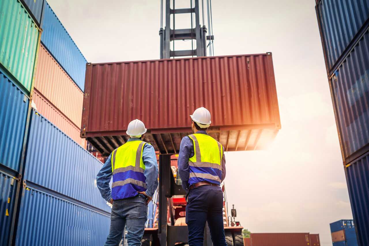 Port workers walking between shipping containers